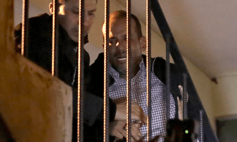 Luis Fernando Camacho, figura clave de la oposición y gobernador de la región económica de Santa Cruz, es escoltado por una escalera a su llegada a la sede de las Fuerzas Especiales de Lucha Contra el Crimen en La Paz, Bolivia, tras su detención el 28 de diciembre de 2022 (AFP)