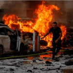 Un hombre corre por una carretera mientras el fuego arde después de que se lanzaran cohetes desde la Franja de Gaza, en Ashkelon, Israel. Foto: REUTERS/Amir Cohen