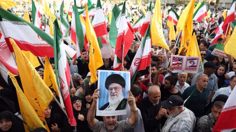 Un iraní sostiene un retrato del líder supremo iraní, el ayatolá Alí Jamenei, entre banderas nacionales de Irán durante una manifestación en Teherán, el pasado martes. ABEDIN TAHERKENAREH (EFE)